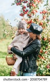 Mom And Her Baby Girl Walking And Picking Apples In The Garden. Harvesting Autumn. Apple Orchard, Wild Garden.