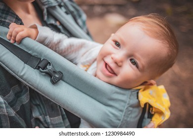 Mom And Her Baby Iin A Kangaroo Backpack Or Baby Carrier While Traveling Through The Mountains And Forests