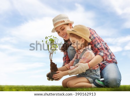 Mom and her child girl plant sapling tree. Spring concept, nature and care.