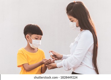 Mom And Her Child Wearing A Medical Mask. Little Asian Boy And Mom Wash Their Hand With Alcohol Gel. Asian Family Protection Virus Concept.