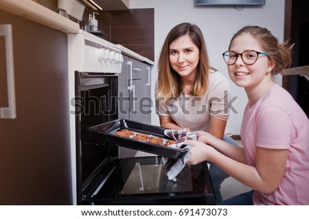Mom and her daughter bake cookies at home in the modern kitchen