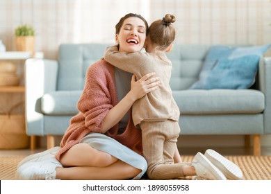 Mom And Her Daughter Child Girl Are Playing, Smiling And Hugging At Home. 