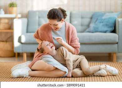 Mom and her daughter child girl are playing, smiling and hugging at home. 