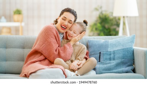 Mom And Her Daughter Child Girl Are Playing, Smiling And Hugging At Home. 