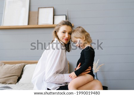 Mom and her daughter cuddling together while sitting on bed