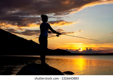 Mom and her little daughter are fishing with a fishing rod on a pier at sunset by the lake - Powered by Shutterstock