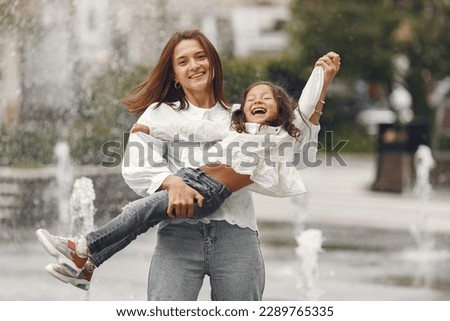 Mom and her little daughter playing by the spray of water