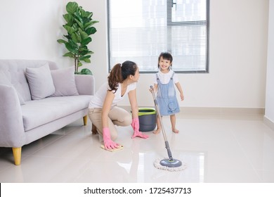 Mom And Her Little Woman Cleaning Living Room Together. Family Housework And Household Concept.