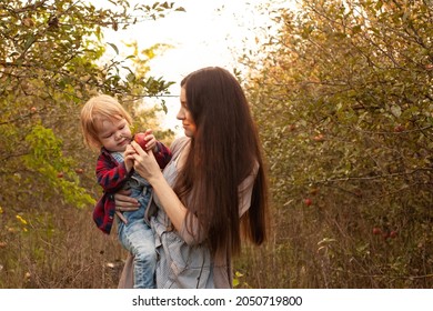 Mom And Her Son Walking And Picking Apples In The Garden. Harvesting. Autumn. Apple Orchard, Wild Garden