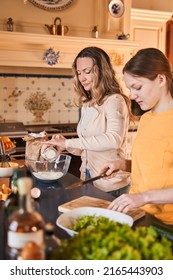 Mom And Her Teen Child Standing In Cooking Room And Making Dinner Together