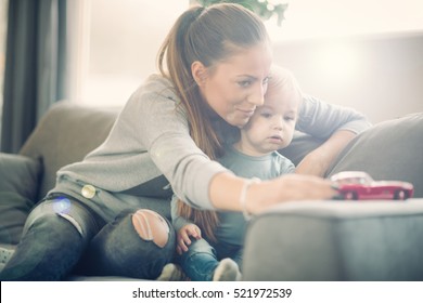 Mom And Her Toddler Son Plays With Red Car In Their Cosy Living Room