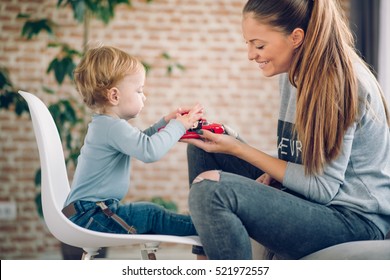 Mom And Her Toddler Son Plays With Red Car In Their Cosy Living Room