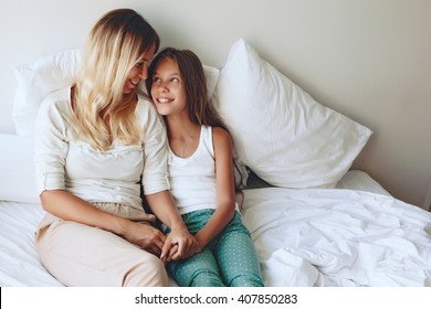 Mom with her tween daughter relaxing in bed, positive feelings, good relations.
