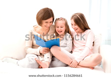 Similar – Mother reading book to her sons in the bed