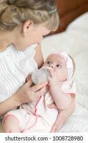 Mom Holding And Giving Milk Formula To Newborn Baby From Bottle