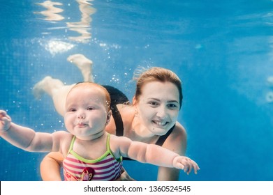 Mom Holds Daughter Are Immersed In Water, Swimming Under Water In Paddling Pool. Diving Baby. Learning Infant Child To Swim. Young Mother Or Swimming Instructor And Happy Little Girl.