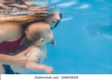 Mom Holds Son Are Immersed In Water, Swimming Under Water In Paddling Pool. Diving Baby. Learning Infant Child To Swim. Young Mother Or Swimming Instructor And Happy Little Boy.