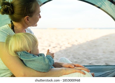 Mom Hugs The Baby While Sitting In The Tourist Tent. Sea And Beach Views From The Camping Tent.