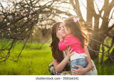 Mom Hugs Kisses Daughter In The Lush Spring Garden, The Family, Motherhood, Spring,