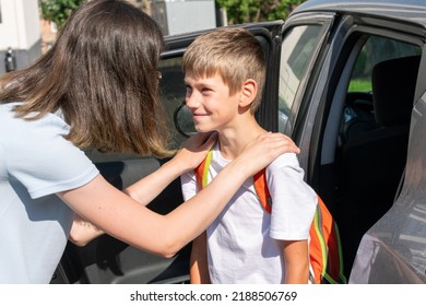 Mom Hugs And Puts The Child With A School Bag In The Car To Take To School. Back To School Concept.