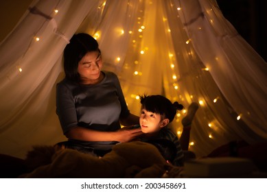 Mom And Kid Bedtime Story In Illuminated Children's Tent, Happy Quality Time, Family Concept Dark Background, Asian Parent.