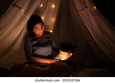Mom And Kid Bedtime Story In Illuminated Children's Tent, Happy Quality Time, Family Concept Dark Background, Asian Parent.