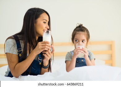 Mom And Kid Girl Drinking Milk On Bed.