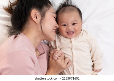 Mom And Kid Are Laying Down And Cuddling. Mom Is Kissing Her Son And Both Are Smiling. Cute Baby Boy Is Look So Happy And Enjoy Playing With Mom. The Baby Has Chubby And Healthy.