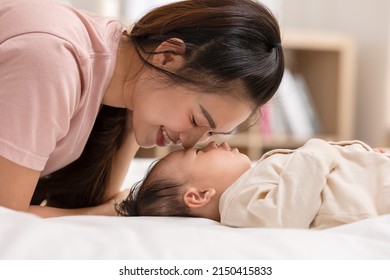 Mom And Kid Are Laying Down And Cuddling. Mom Is Kissing Her Son And Both Are Smiling. Cute Baby Boy Is Look So Happy And Enjoy Playing With Mom. The Baby Has Chubby And Healthy.