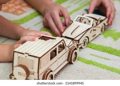 Mom with Kid playing eco Wood puzzle 3d cars at home on carpet with road. The concept of learning 
accident on road traffic rules childhood. Wooden toys for boy