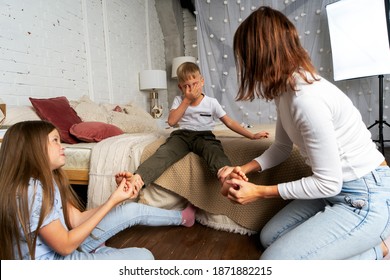 Mom And Kids Have Fun In The Bedroom And Tickle Each Other's Feet. The Older Sister Helps Tickle The Legs Of The Younger Brother.