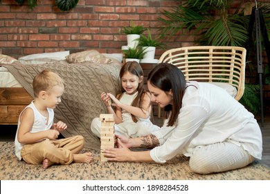 Mom And Kids Play Squirl Jenga Tower. Woman Girl And Boy Play Family Puzzle Game. Family Day Off