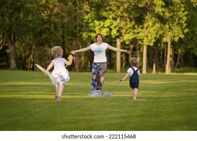 Mom With Kids Playing In The Park. Children Run To Meet Mom