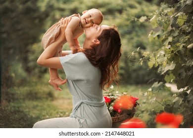 Mom Kisses Her Baby Boy In A Green Garden