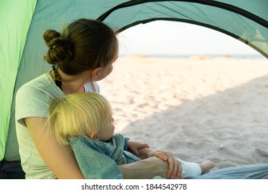 Mom With Little Baby Sitting In The Tourist Tent. Sea And Beach Views From The Camping Tent.