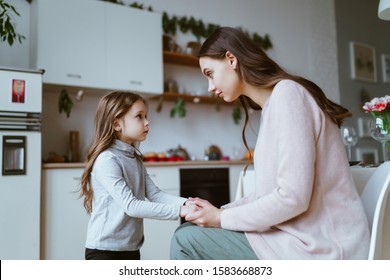 mom with a little daughter in the kitchen. the girl tells something and mom listens carefully to her - Powered by Shutterstock