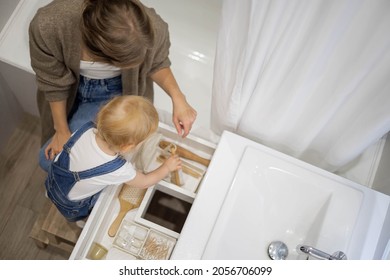 Mom And Little Daughter Organizing Bathroom Storage, Displaying Beauty Cosmetic Creams And Toiletries Into Drawer With Dividers. Bathroom Vanity Decluttering Concept By Using KonMari Method.