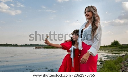 Mom and little daughter are walking by the lake. Happy family spend time together. Mother and girl having fun by the pond