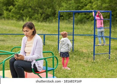 Mom Looks At Her Phone And Does Not Monitor Children At The Playground