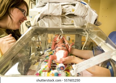 Mom looks on as nurse holds up preemie baby girl 