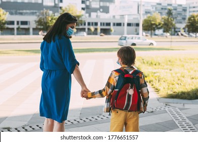 Mom With A Masked Child Go To School Or Kindergarten. Parents And Children In A Mask During A Coronavirus. Back View