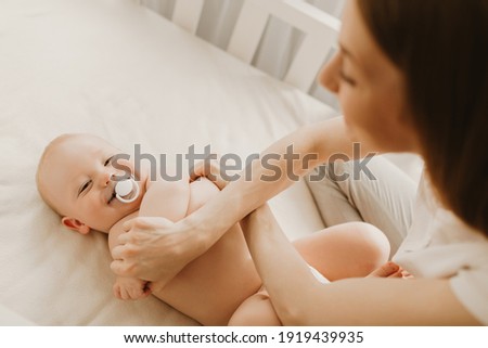 Mom massages newborn baby, gymnastics, physical fitness, strengthening exercises for babies, early development, health care concept