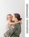 mom in military flight suit hugs and kisses daughter