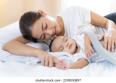 Mom And Newborn,Happy Family Concept.Close Up View Of Beautiful Asian Mother And Her Sleeping Newborn Baby.Mother Holding Baby Hand In One Hand And Holding Hand The Baby With Eyes Closing And Smiling.