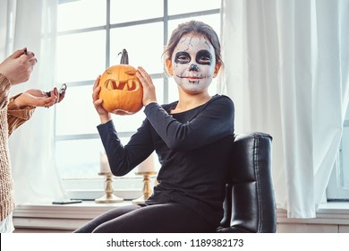 Mom Painting Daughter Face For Halloween Party.