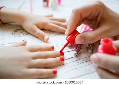 mom paints daughter's nails on hands with red nail Polish on white table, beautiful nails concept, manicure - Powered by Shutterstock