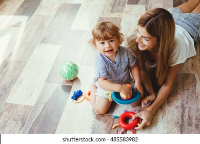 Mom Playing With Her Son With Toys On The Warm Clean Floor At Home