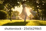 Mom plays with child, twists happy smiling cute child by arms in park, sunset. Mother, child playing together on lawn in sun. Mom, little daughter have fun playing. Family, child, weekends, nature