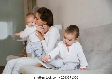 Mom Plays And Reads Books With Two  Little Kids. Mother Spends Time With Two Child Sons At Home.  Place For Text. Copy Space. Family Time At Home
