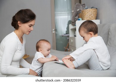 Mom Plays And Reads Books With Two  Little Kids. Mother Spends Time With Two Child Sons At Home.  Place For Text. Copy Space. Family Time At Home
